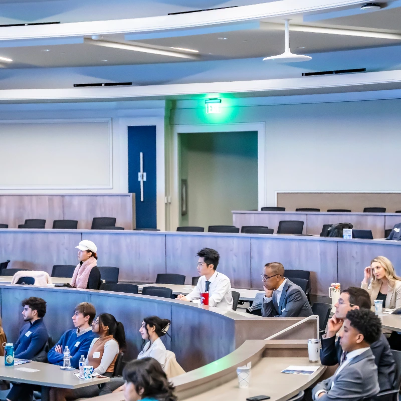 Diverse group of students and professionals attentively listening in a modern lecture hall setting.