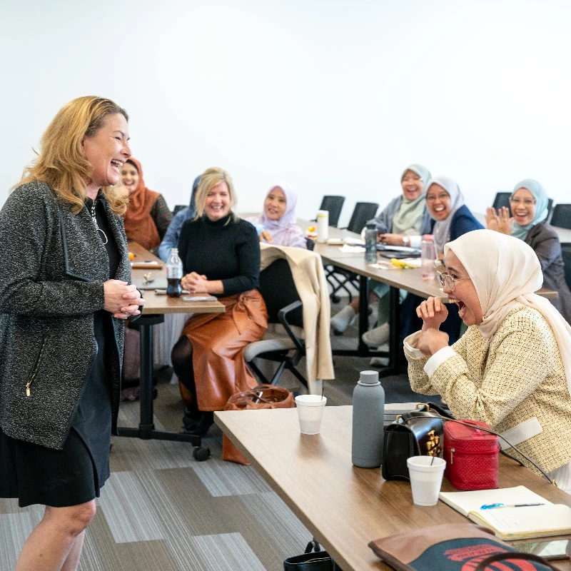 Diverse women laughing during a dynamic professional workshop or training session.