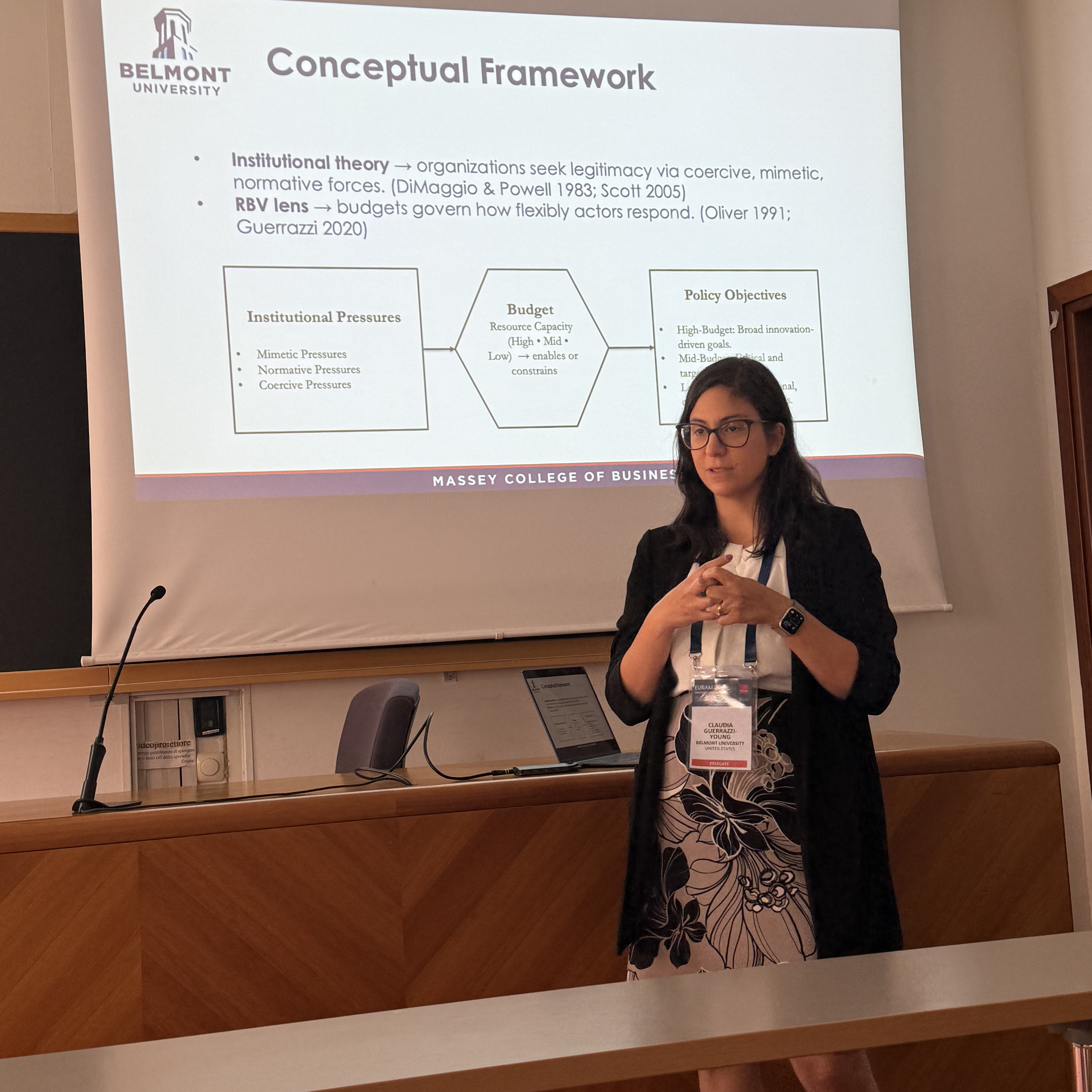 Dr. Claudia Guerrazzi Young presenting at conference while standing in front of slide show.