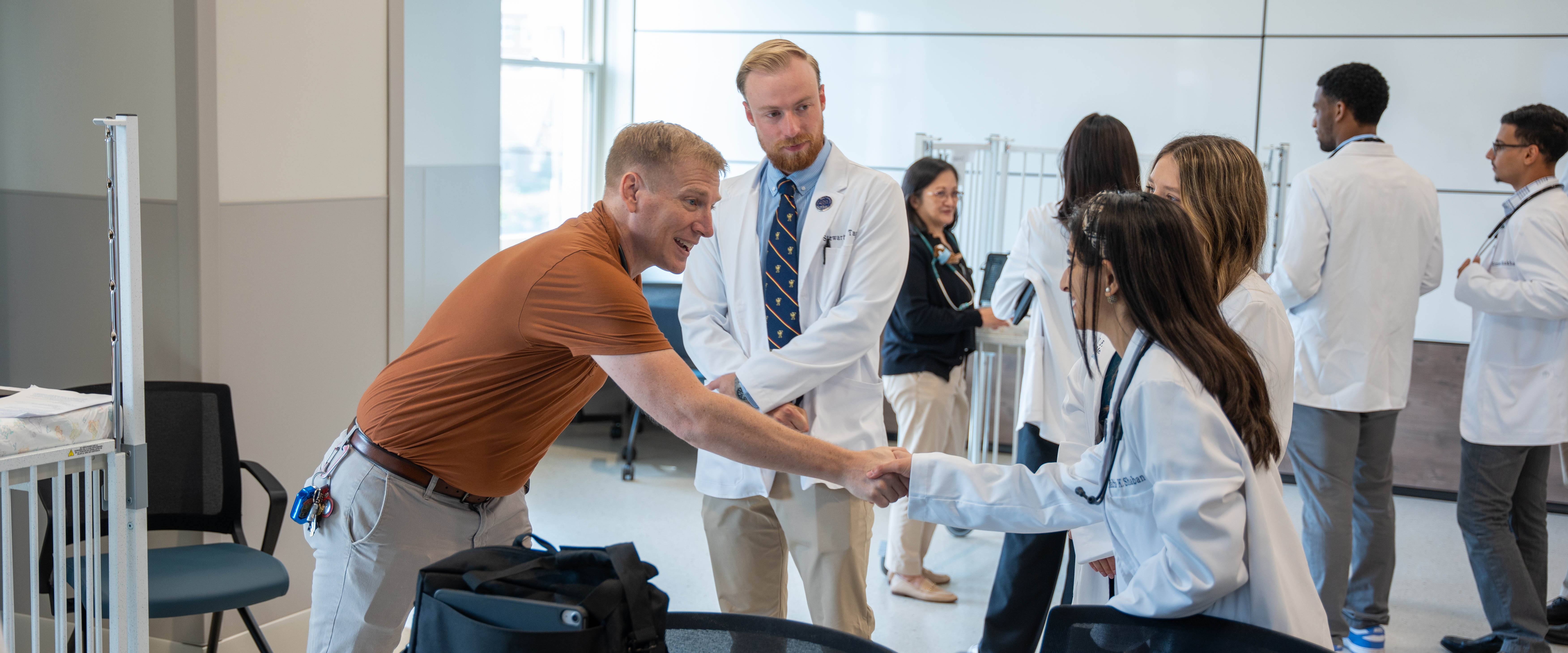Two people shaking hands in a medical environment, symbolizing networking and professional connections.