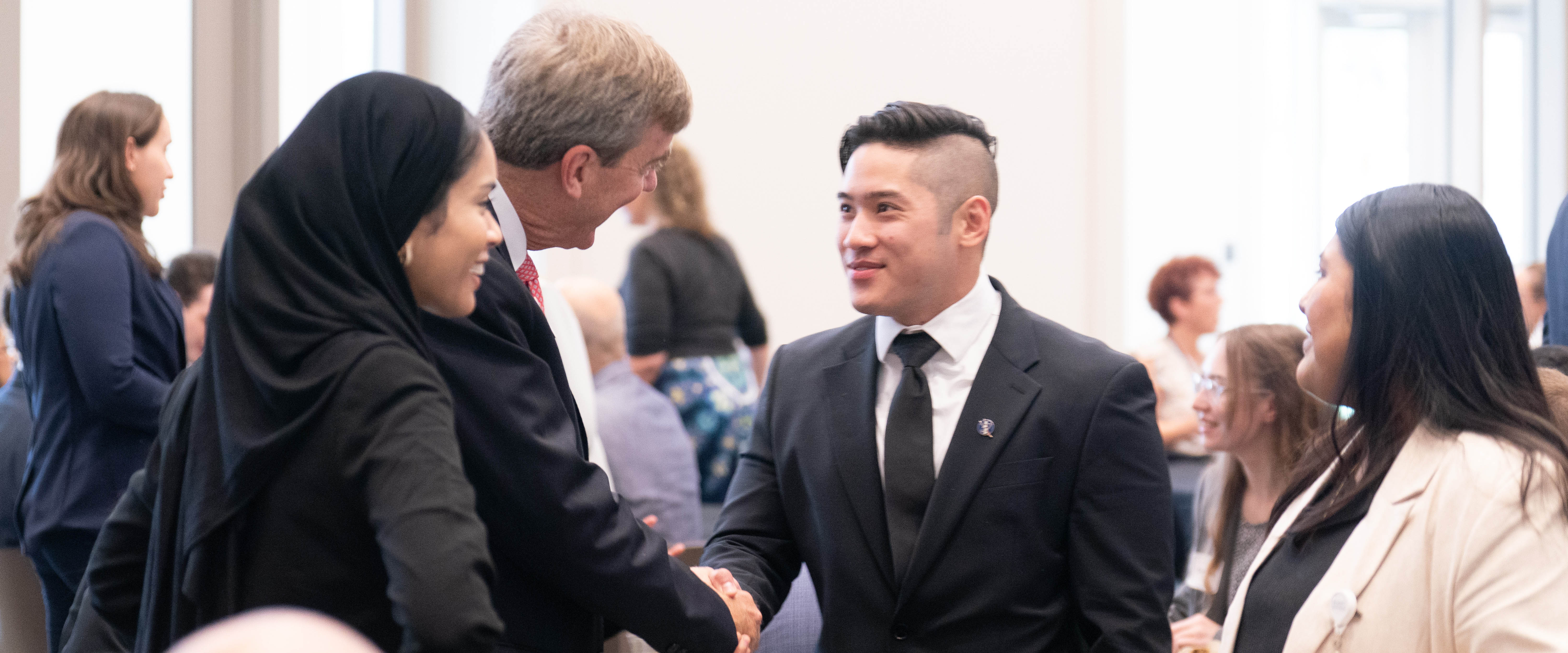 People in business clothes at a networking event for the College of Medicine
