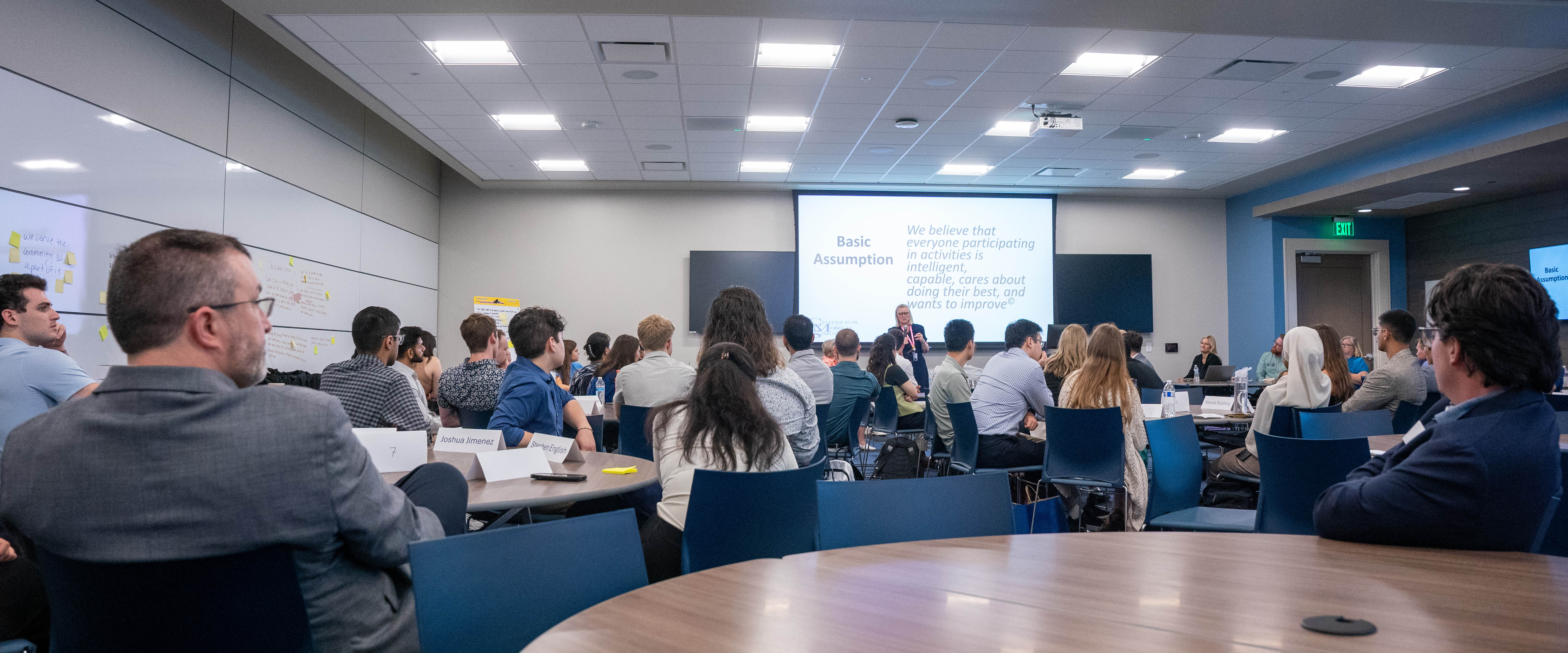 A groups of students in a classroom listening to a professor teach 