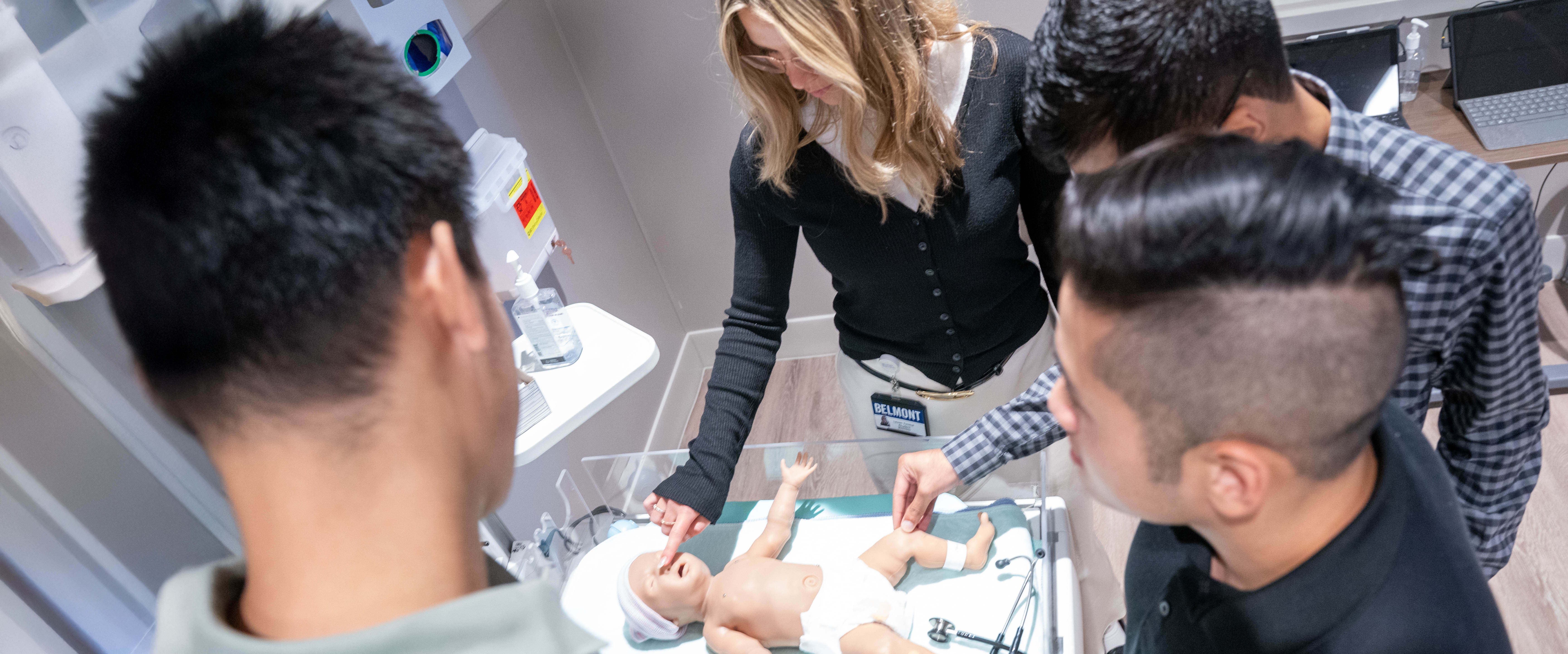 Students gathered around an infant medical manikin in a lab