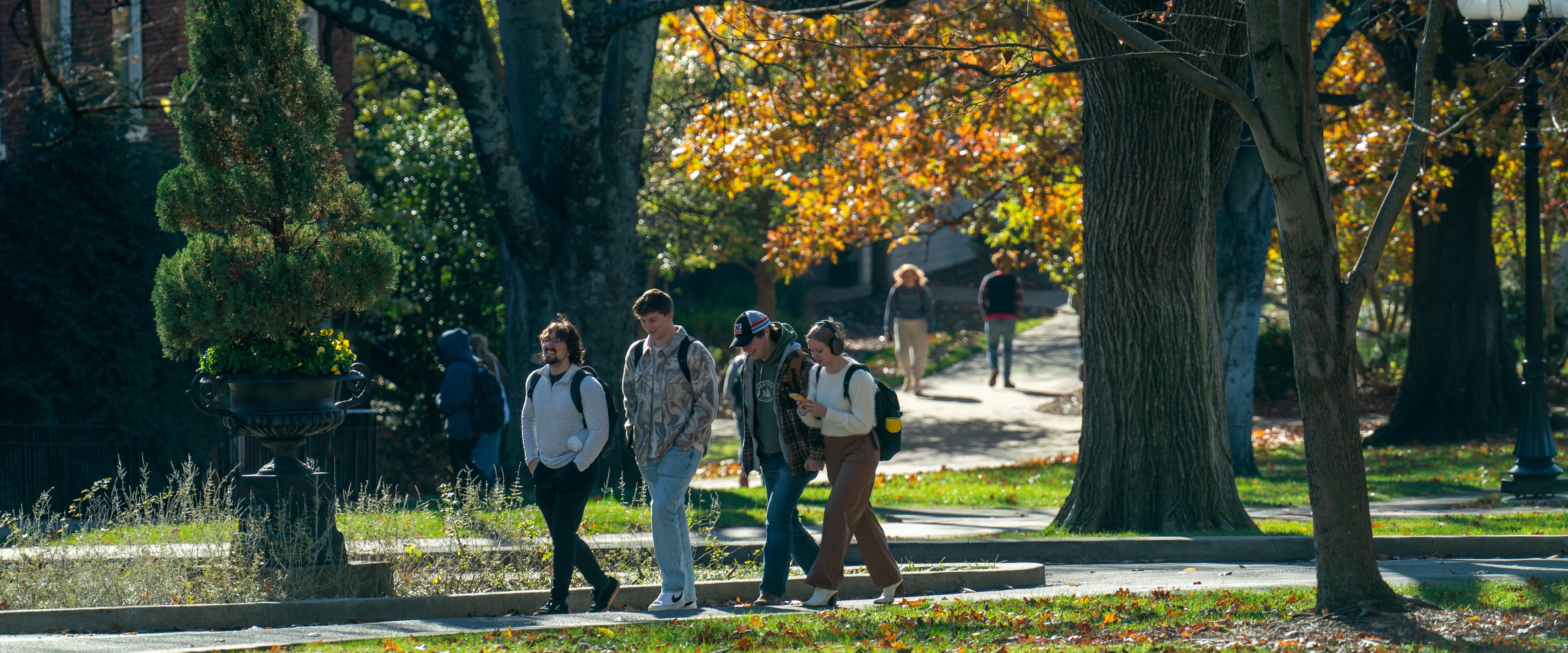 Students walking together outside laughing on a cloudy fall day