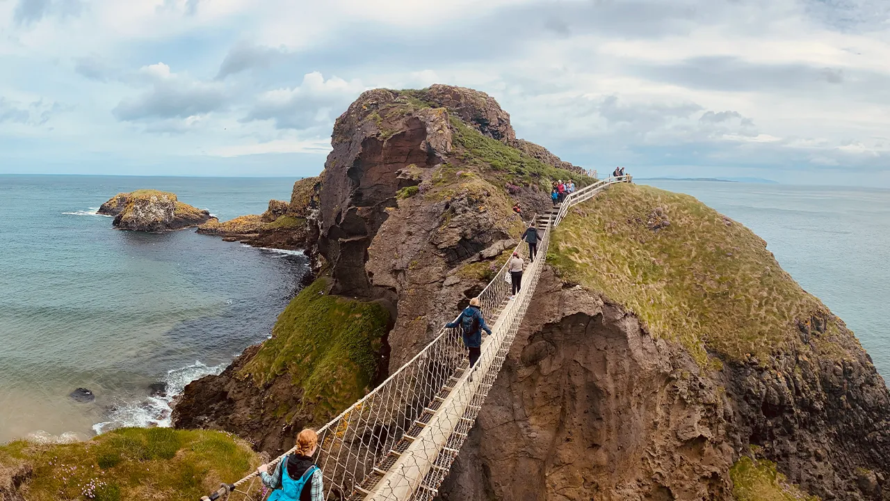 Students crossing a bridge to a sea stack in Ireland