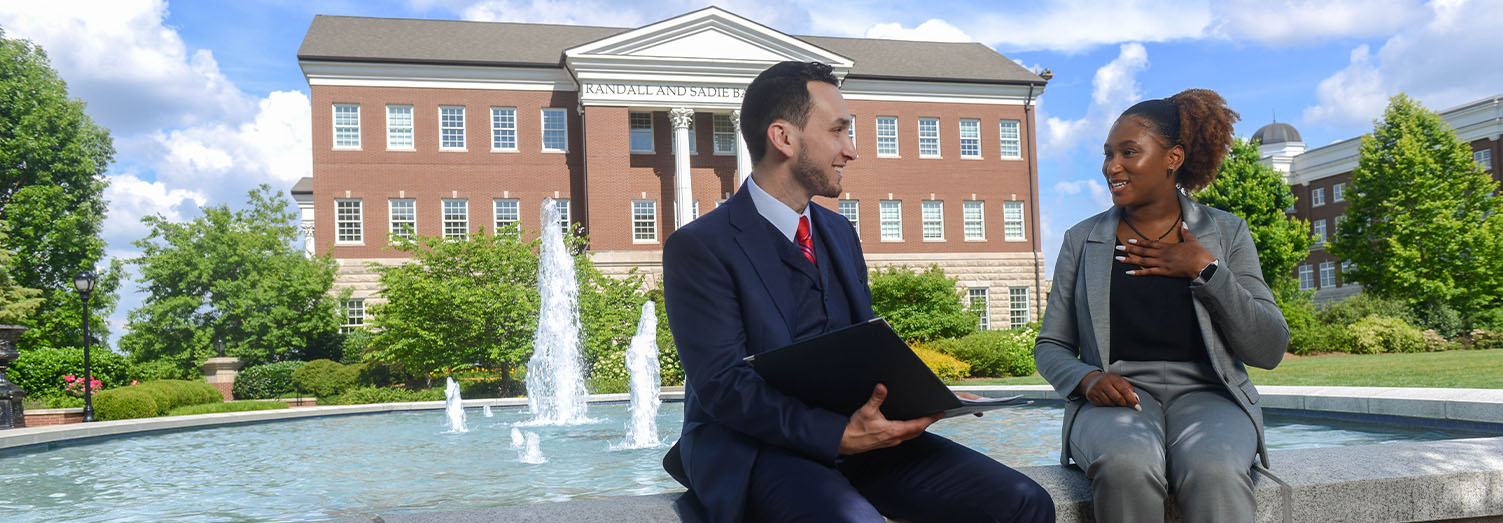 Two students sitting on the Freedom Plaza fountain in front of the Baskin Center