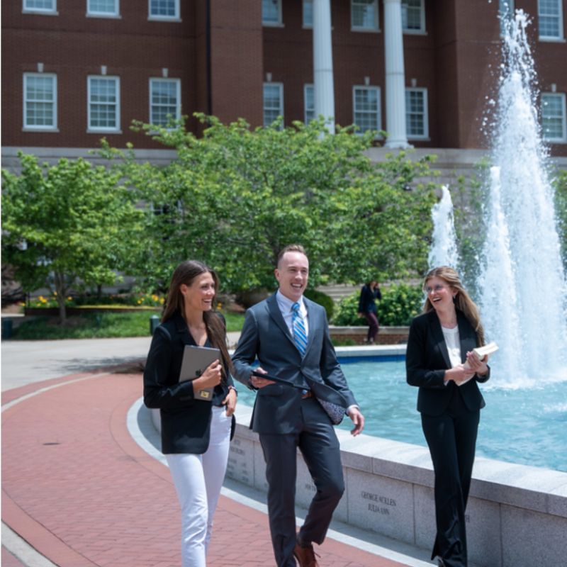 students conversing as they walk near fountain in front of the Baskin Law Building