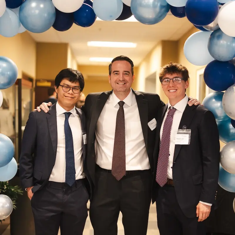 Three law students posing under a ballon arch