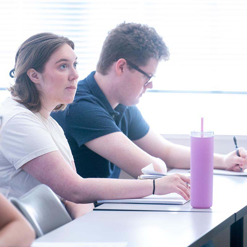 Student taking note and listening to teacher talk during class