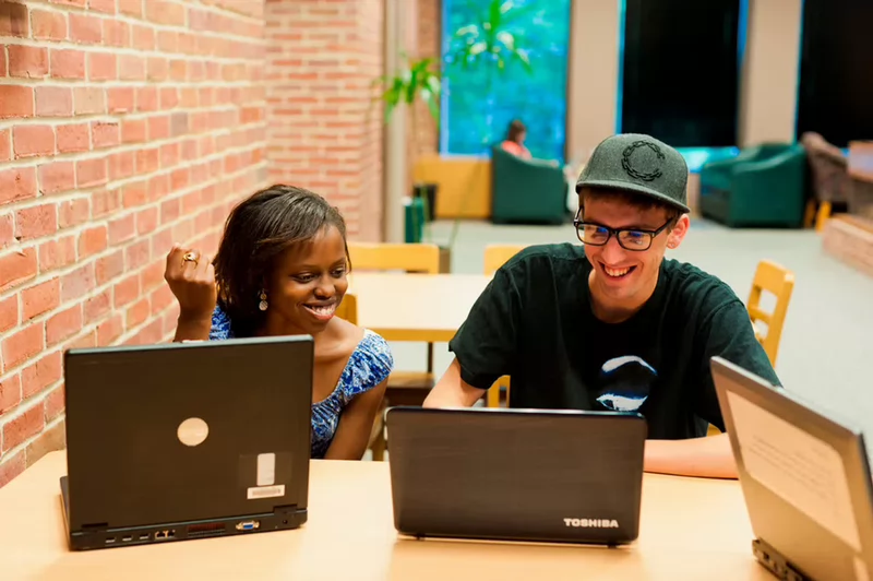 Library visitors collaborating while working on their laptops
