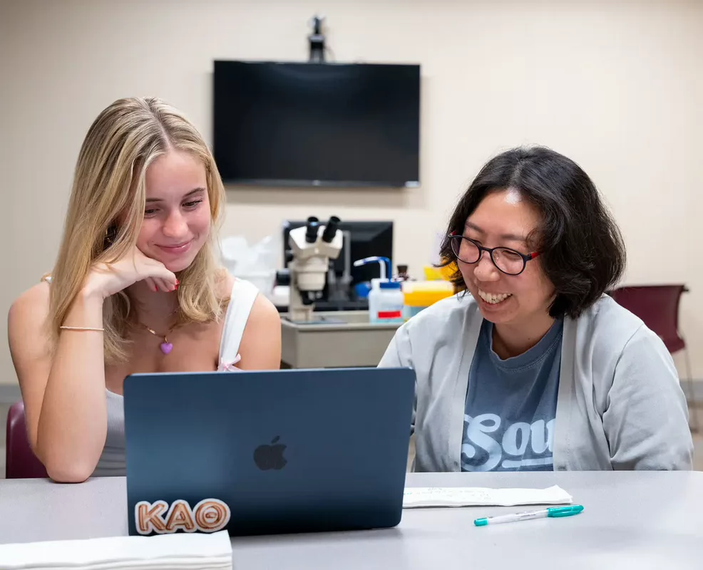 A smiling student working on a laptop.