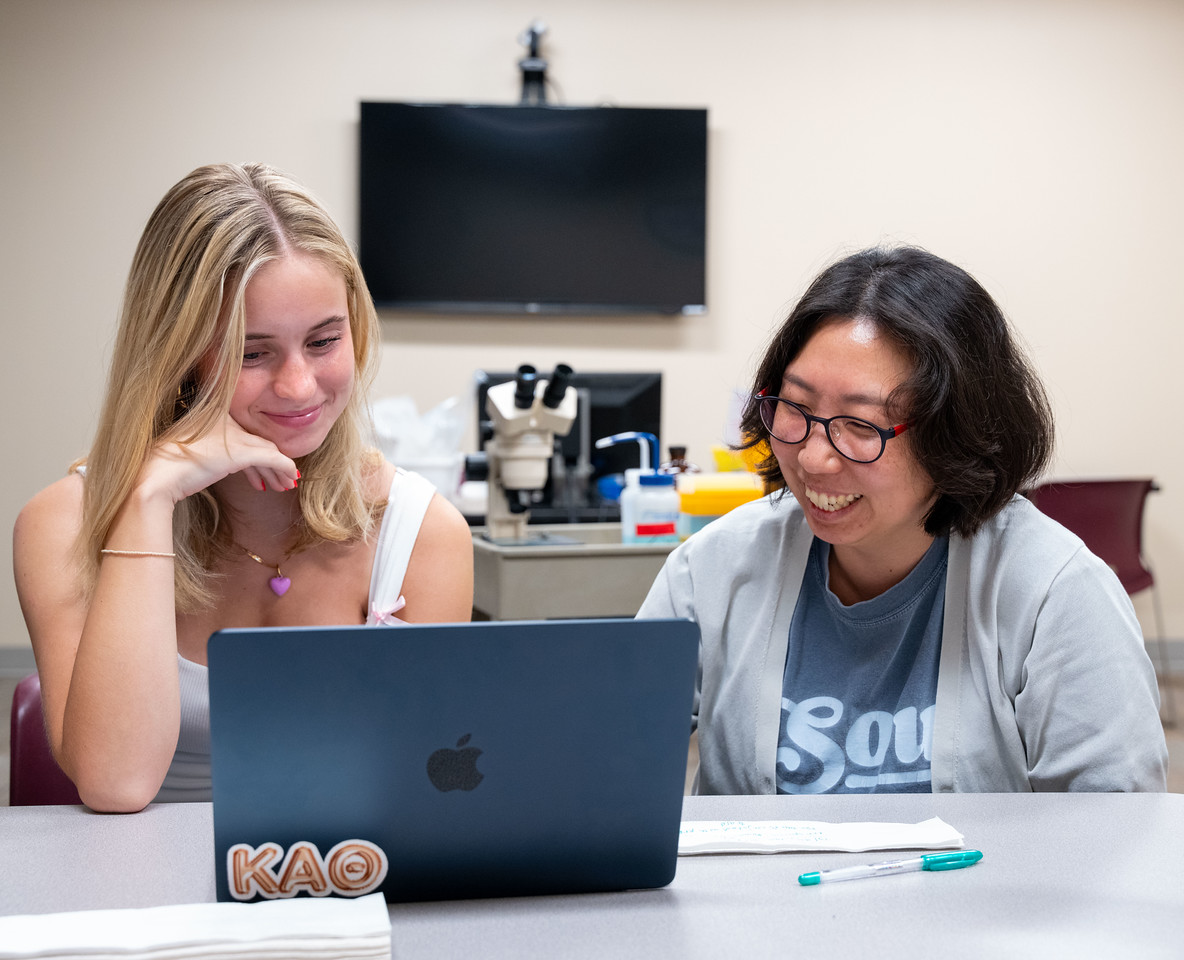 A smiling student working on a laptop.