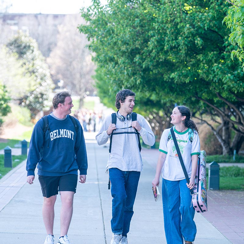 3 students walking to class while laughing and smiling
