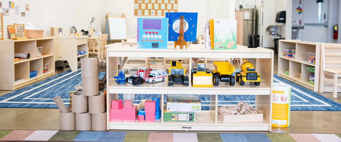 Early childhood classroom with shelves of books, toys and learning materials arranged for children.