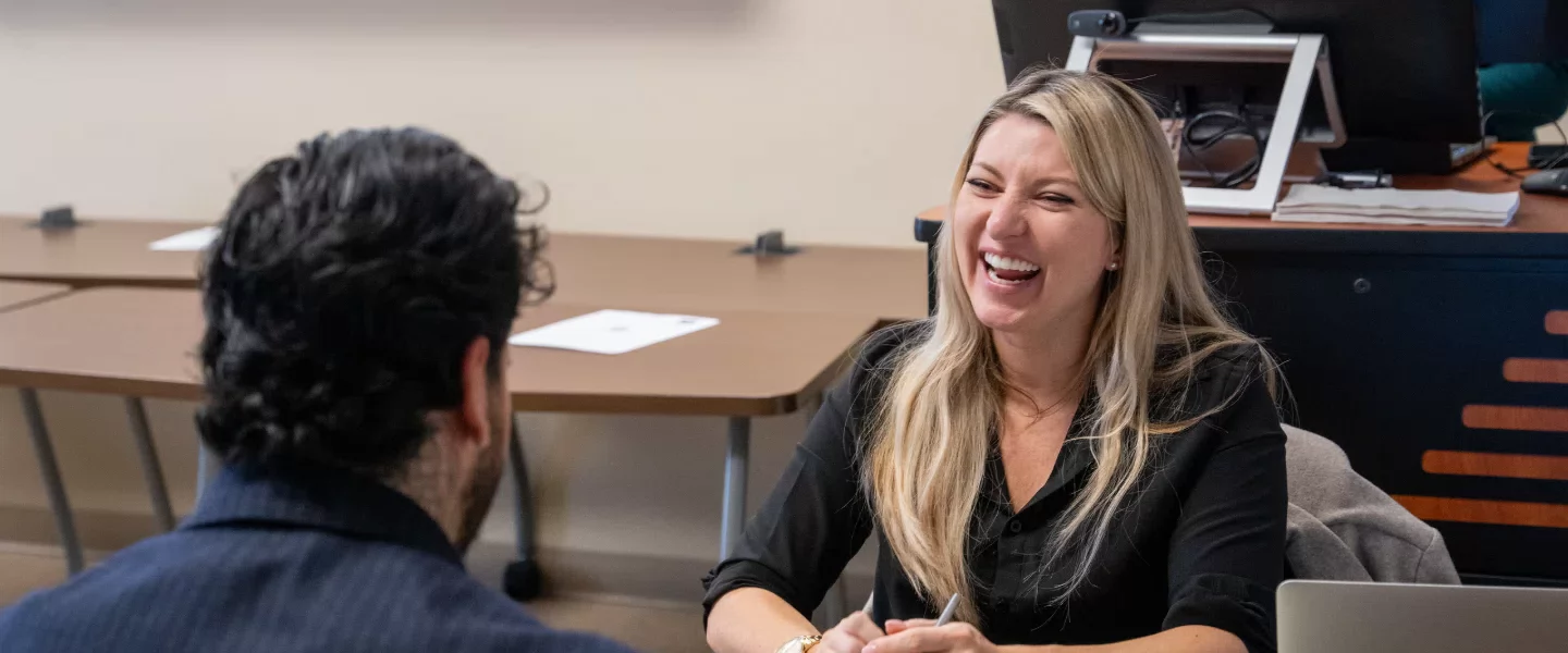 Professional woman laughing with a man during Belmont Powerskills conference.