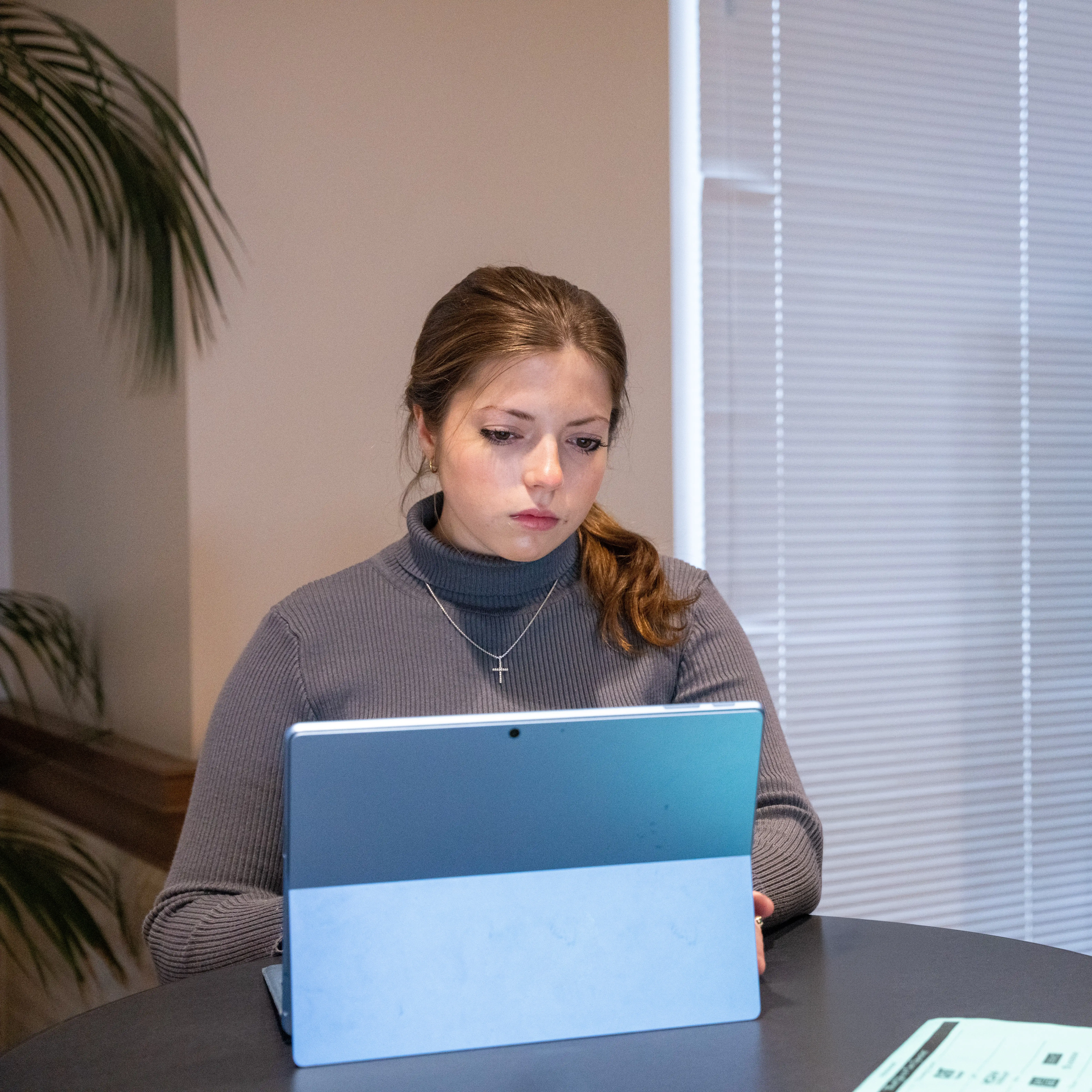 Student working on a laptop at a table in a study or advising space.