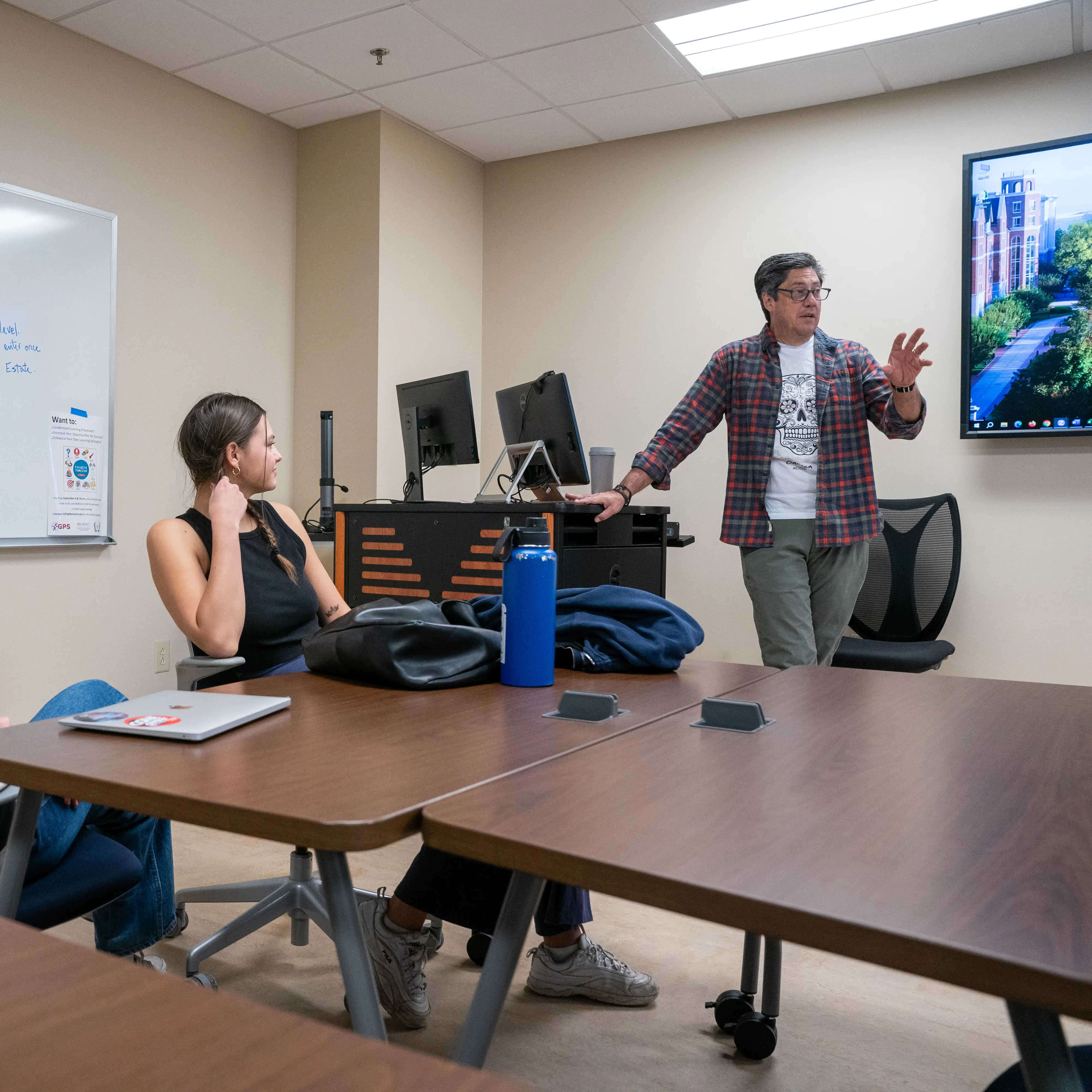 Professor leading a classroom discussion while students listen in a seminar-style setting.