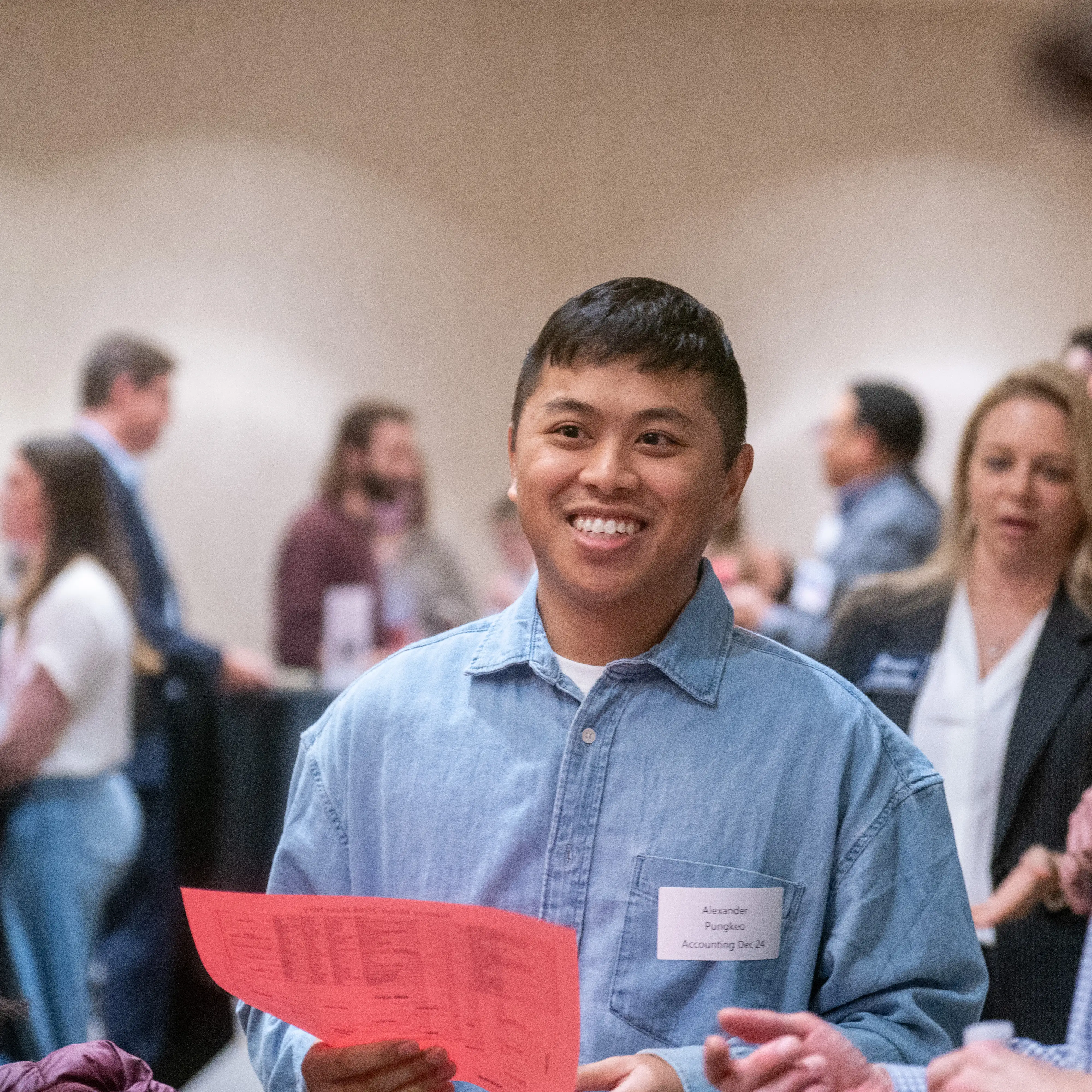 Student smiling while engaging in conversation during a campus networking event.