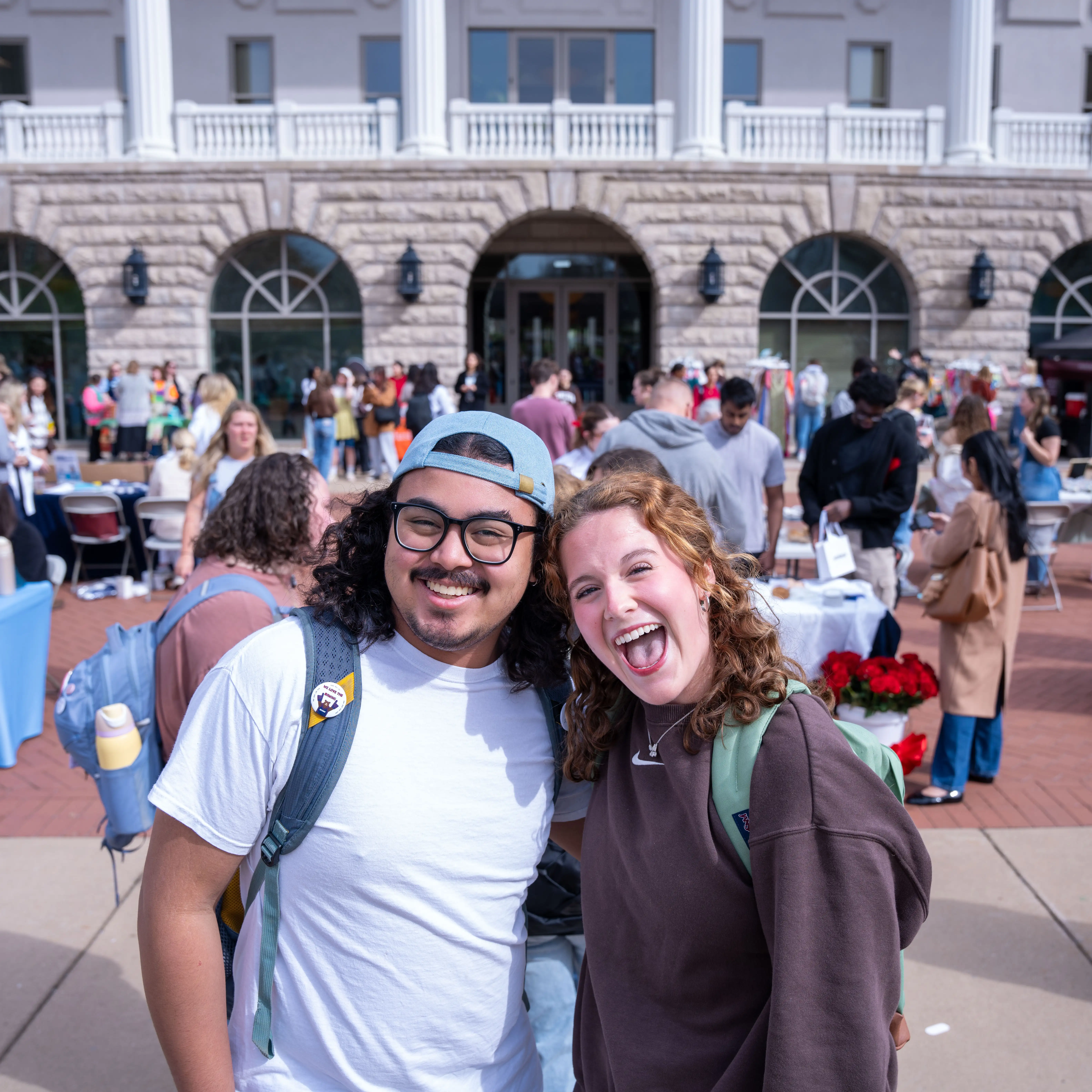 Two students smiling together on campus during an outdoor student event in front of the Jack C. Massey Center.