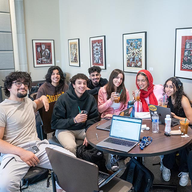 Students sitting and smiling for picture at table in the JAAC