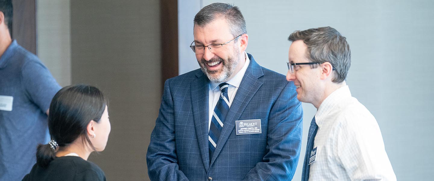 Faculty members smiling and laughing while talking in a small group