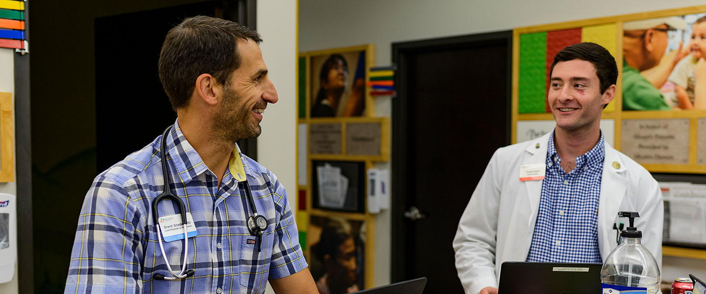 A doctor smiles and talks with a patient in an office