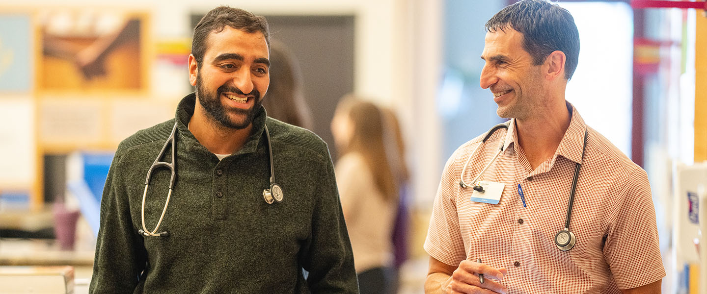 A medical student walking and talking with a medical faculty member