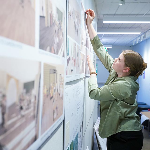 Student hanging project on the wall of O'More College