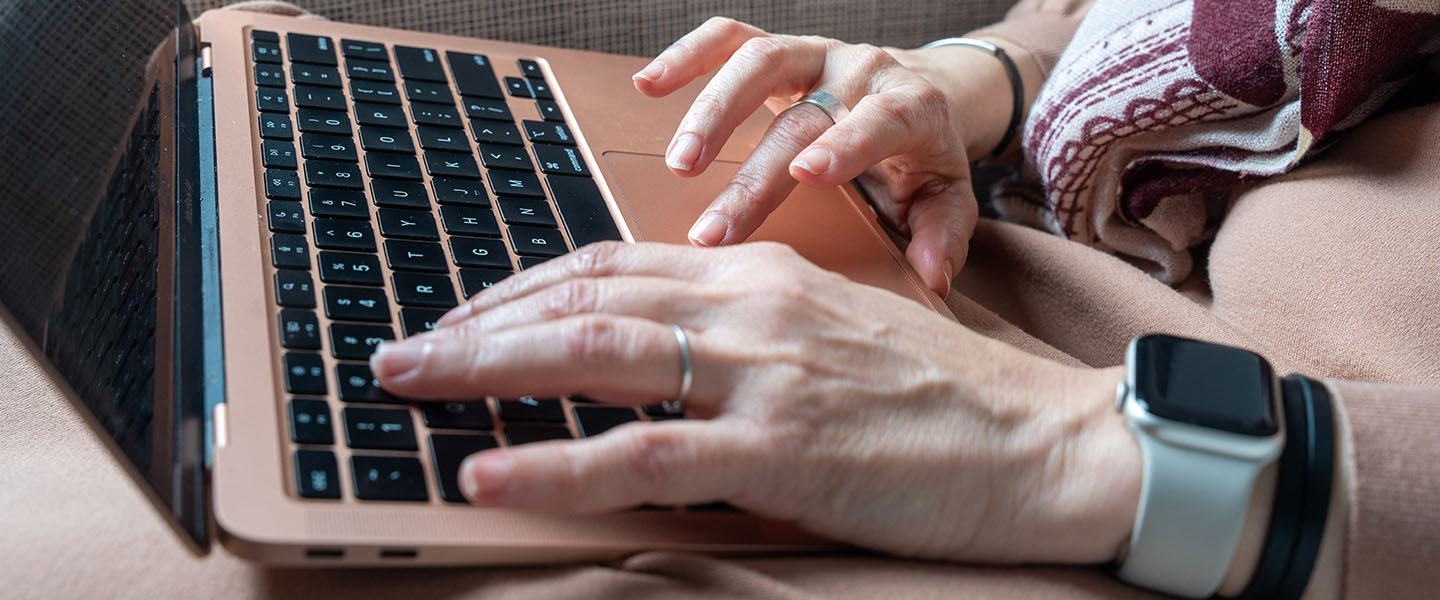 A pair of hands type on a laptop keyboard