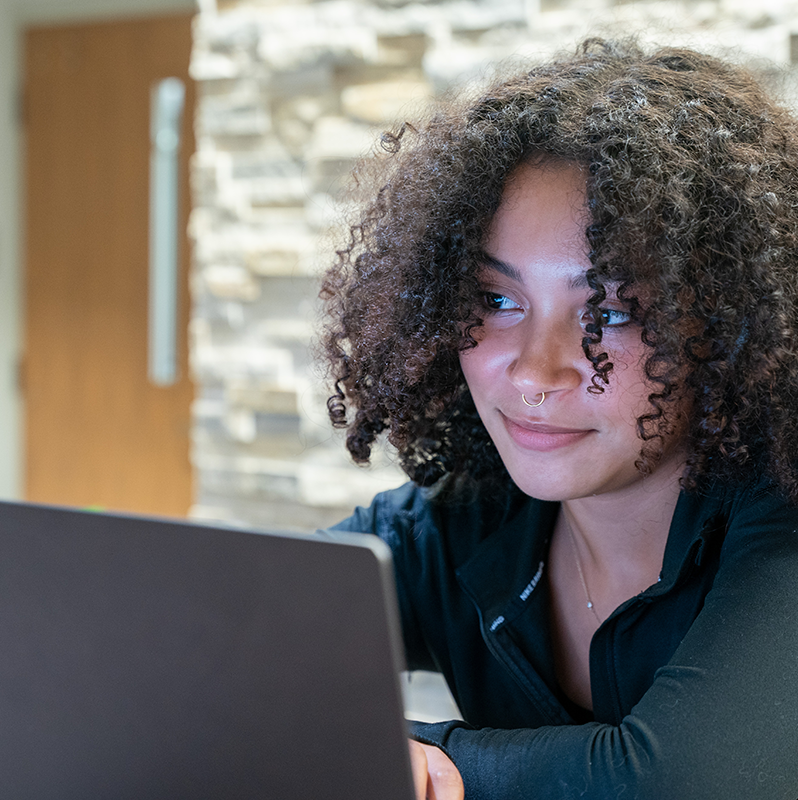 Young student with laptop with a soft smile.