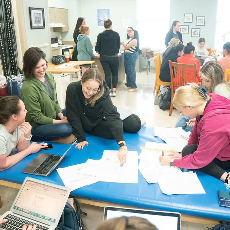 Group of students gathered together working on a class assignment in home health lab