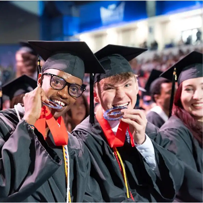 Two joyful graduates holding their medals and smiling at the graduation ceremony