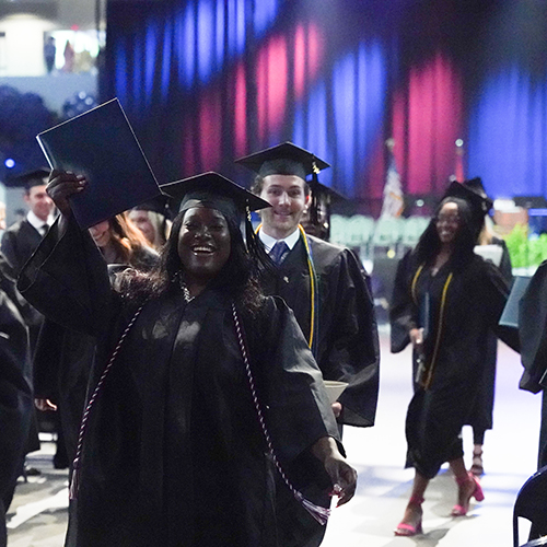 Graduate waving her arm with diploma in hand