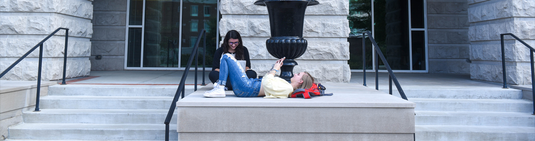 A photo of two Belmont students sitting outside studying on campus.