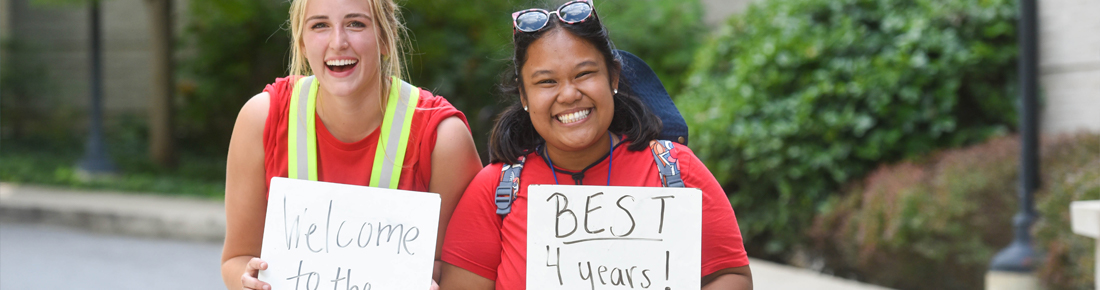 A photo of two Belmont students on move-in day holding signs that say "Welcome to the," and "best four years"