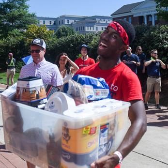 A photo of a male Belmont student carrying a large crate of supplies.