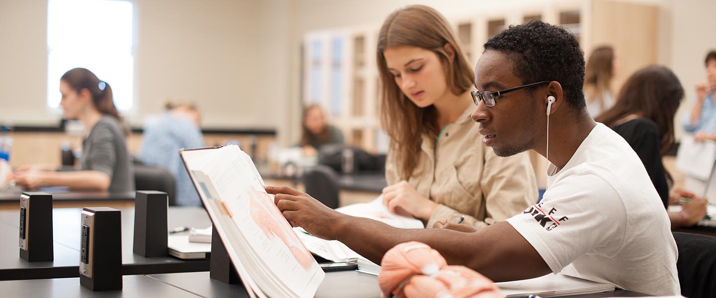 Two students study from a textbook in class