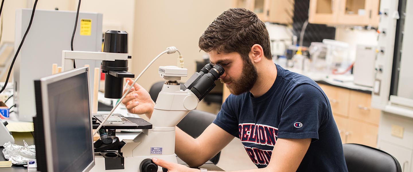 Student looking into microscope in classroom