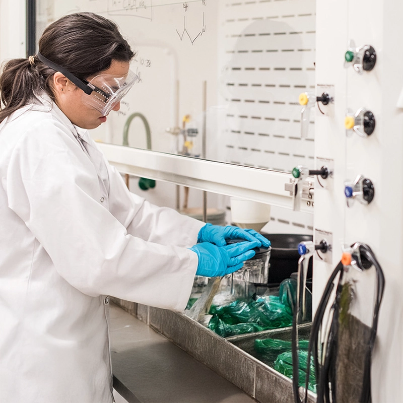 Belmont University student conducting a science experiment in a laboratory with safety goggles and gloves.