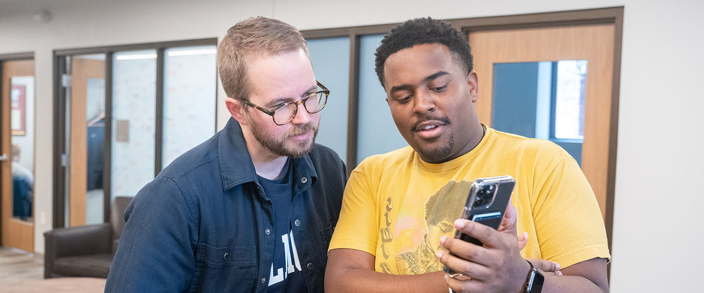 A student worker showing his phone to a staff member