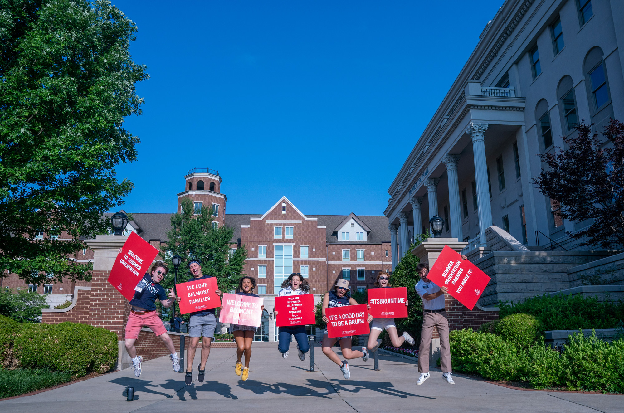 students jumping in the air holding signs