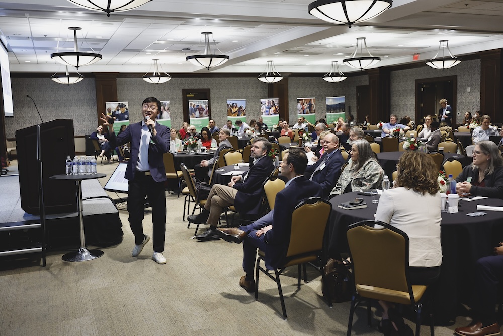 Speaker at LearningWell gestures in front of crowded room of LearningWell participants