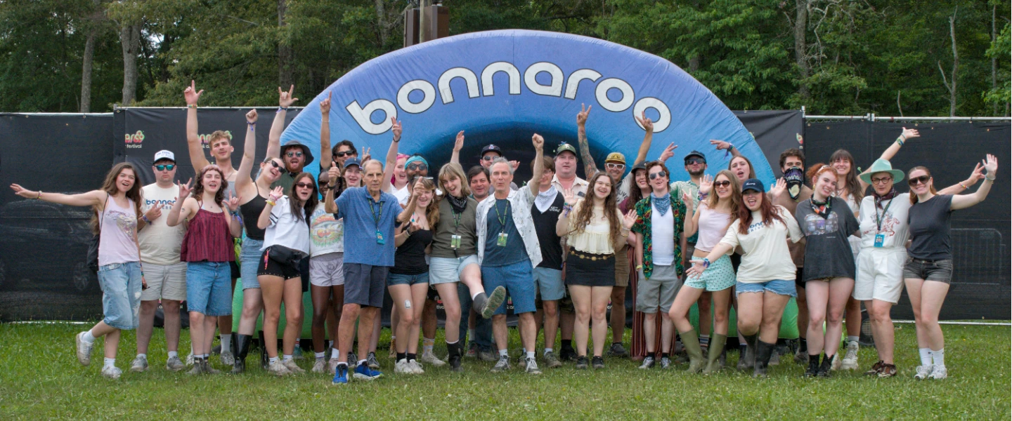 A group of smiling students and faculty outside on a sunny day