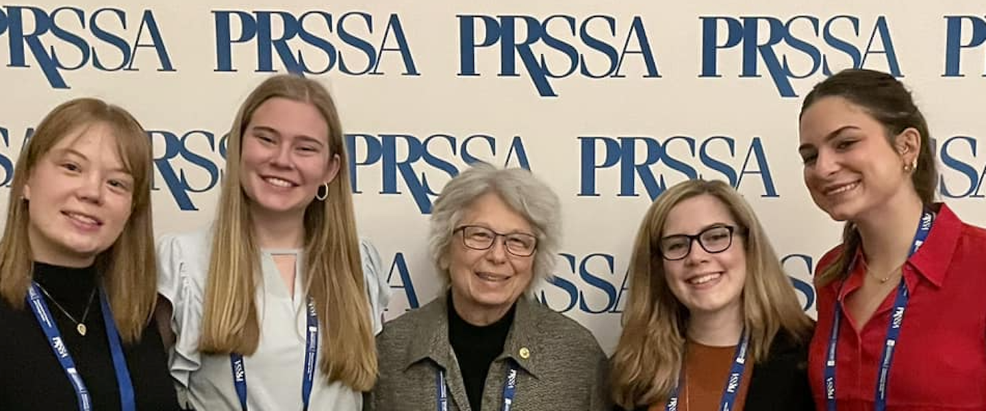 Belmont students and professor Bonnie Riechert in front of PRSSA step and repeat