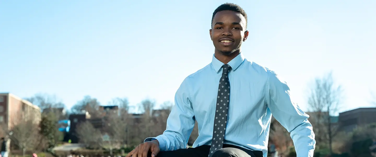 A man seated on a ottoman outdoors on a sunny day
