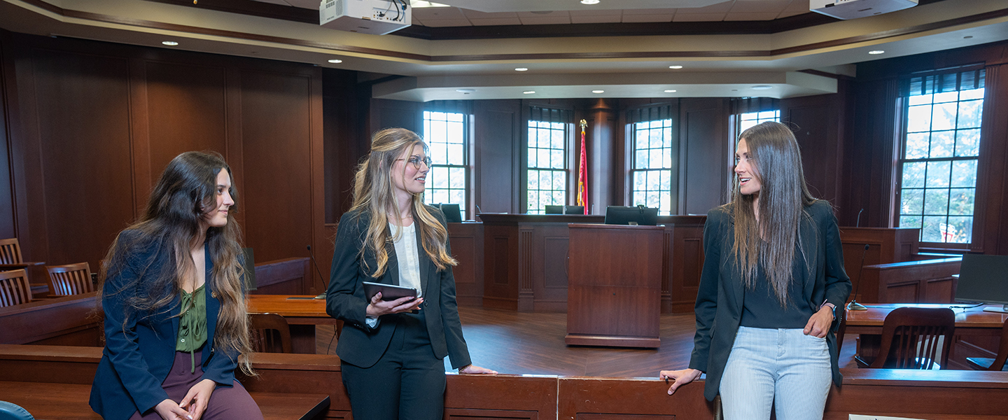 Three female law school students conversing in a court room.