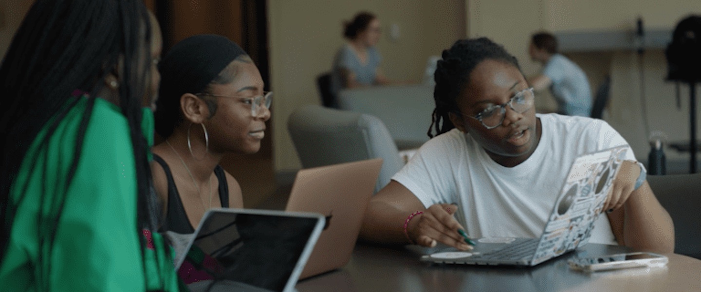 Awonuga works on a computer with friends
