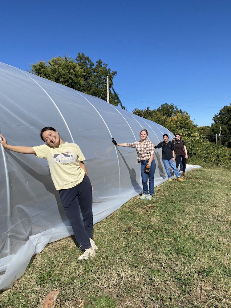 Memphis Plunge group unfolds large plastic sheet for greenhouse at The Works Urban Farm