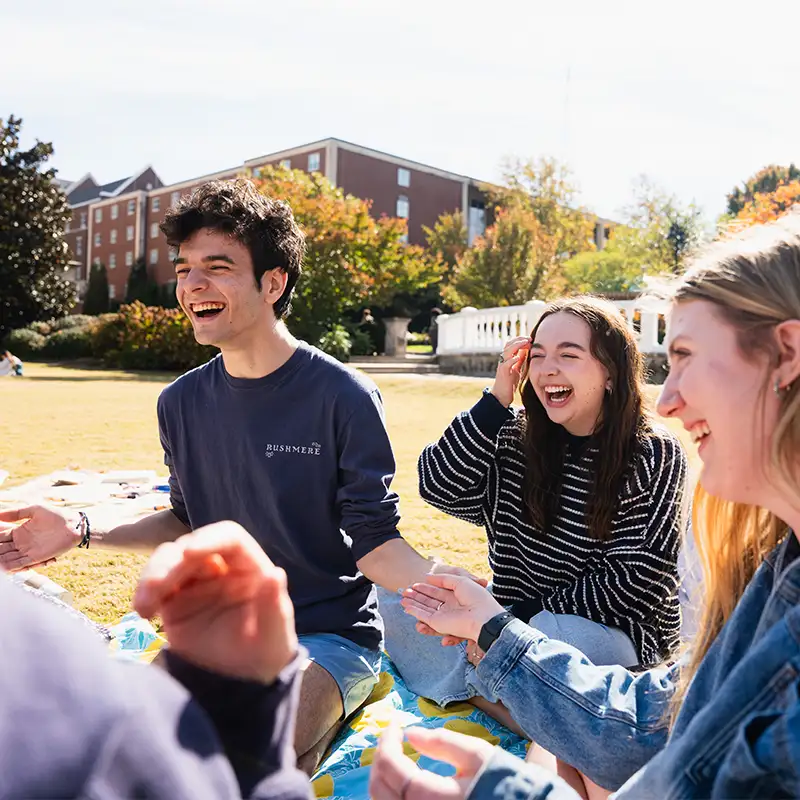 Group of students laughing and playing games on a sunny day on the lawn at Belmont University