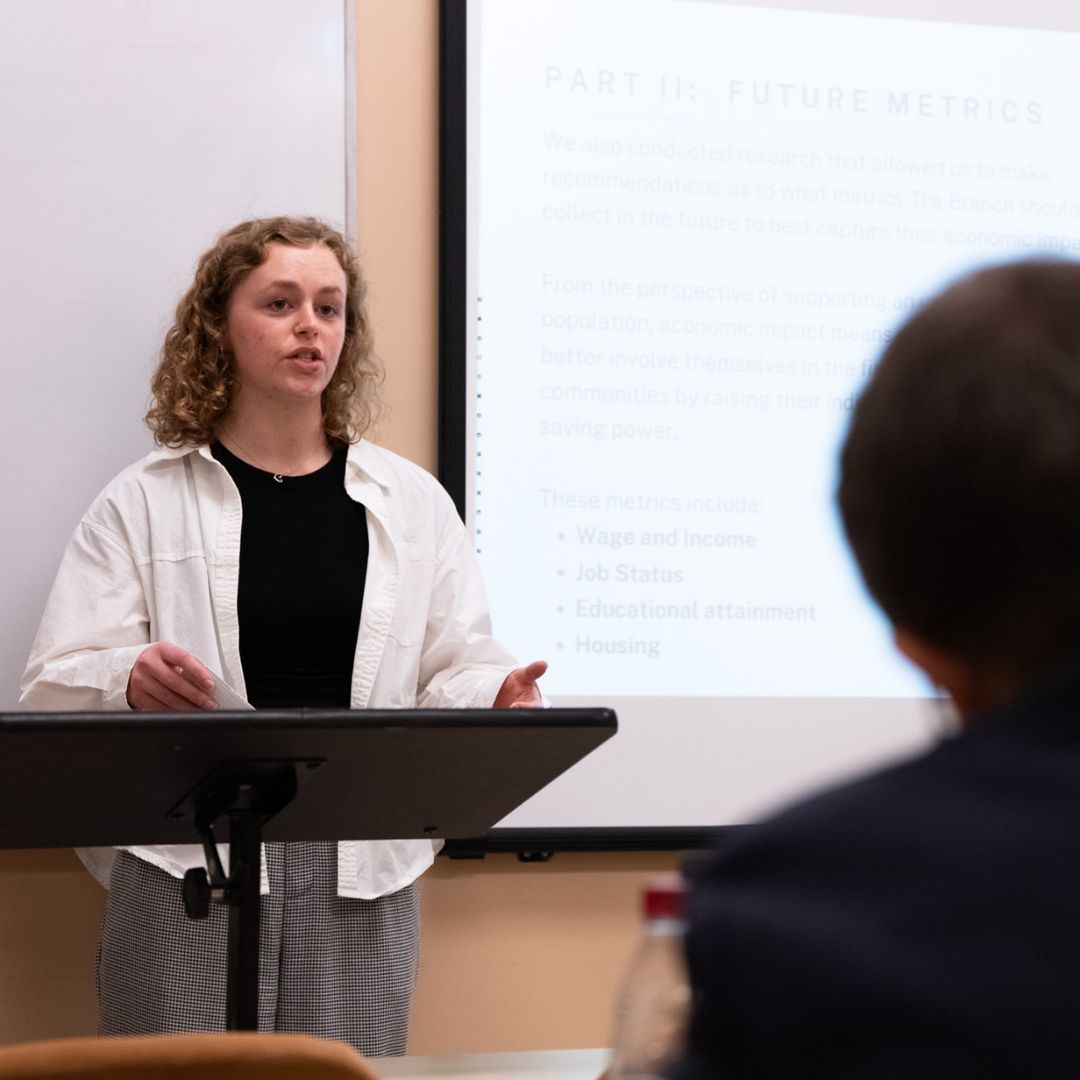 Student presents their research on a screen in front of their classmates